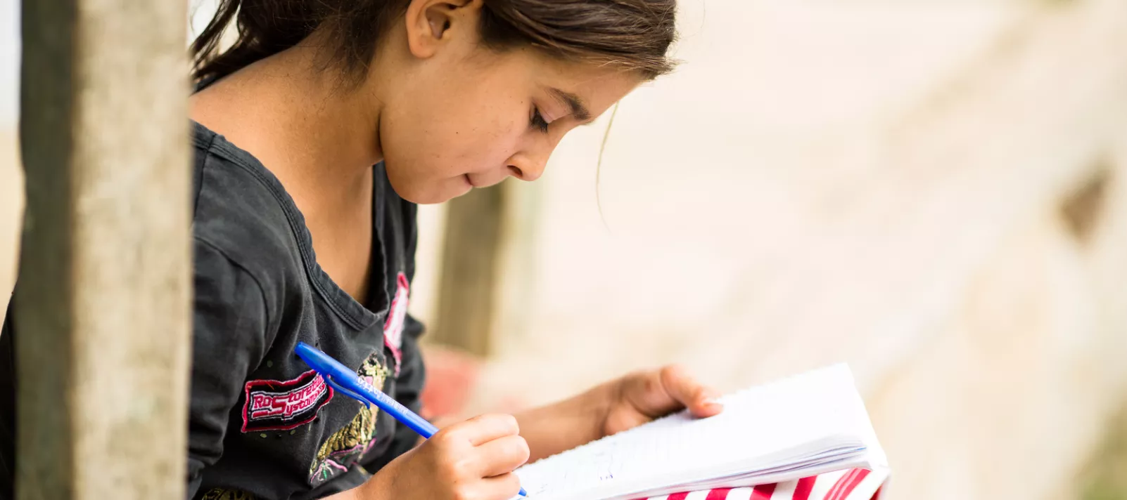 Loredana, 11 years old, sits doing her homework on her porch at her home in Romania.