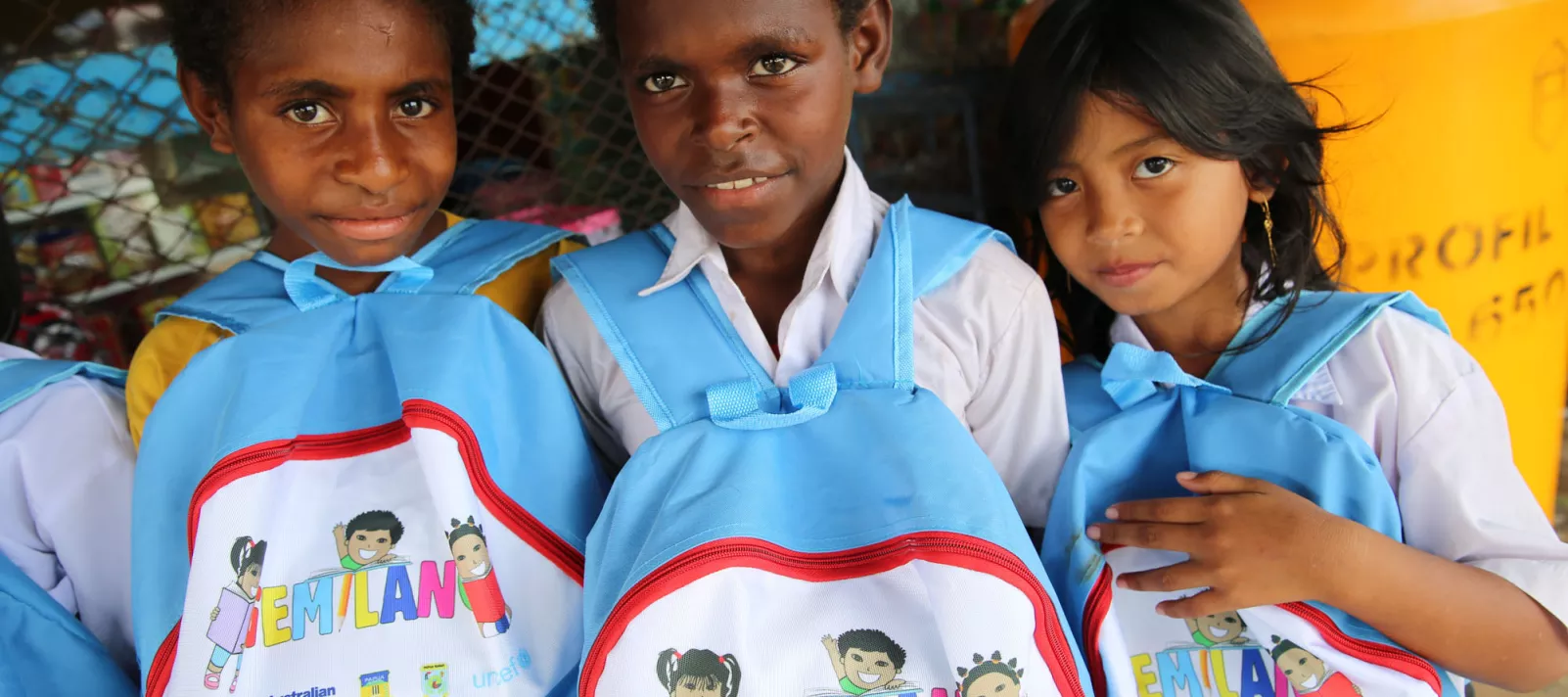 Three children posing with their school bags.