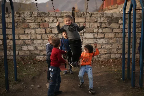 Children riding a swing in the playground of a kindergarten