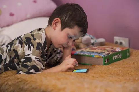 Child reading on a mobile phone at home