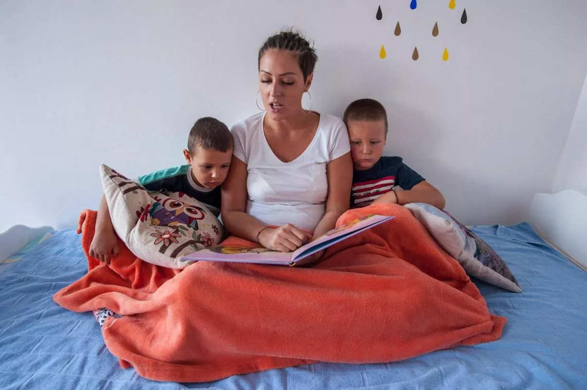 Mother Tanja Pesic reads a book to her two sons in Serbia.