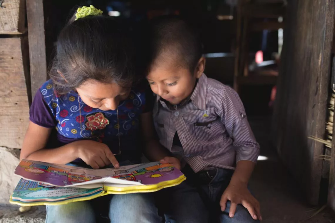 A girl teaches her brother to read in Santa Ana Panquix, Altaverapaz, Guatemala.