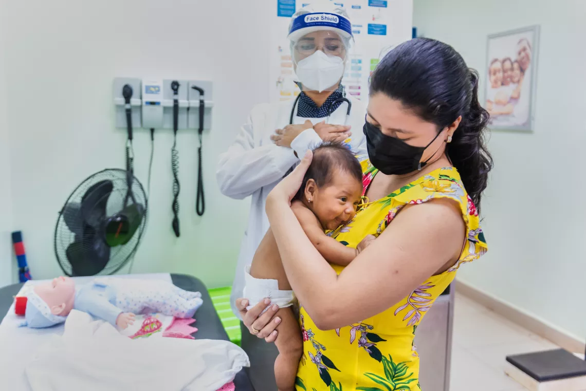 Una madre cargando a su bebé durante una visita rutinaria al pediatra.