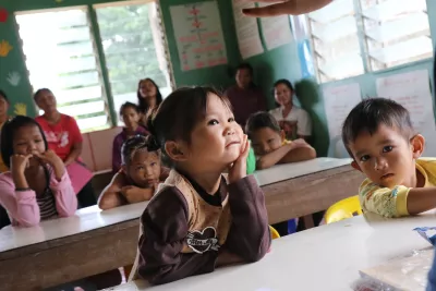 Girl stares ahead with head on palm in classroom
