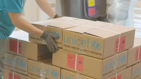 A person stacks boxes with UNICEF labels