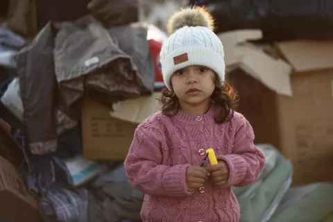 A little girls stands amongst boxes of supplies