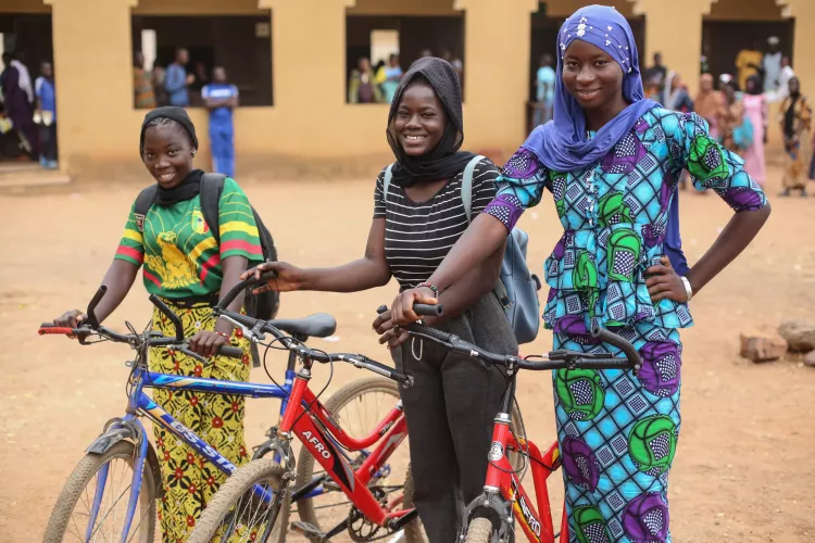 Three girls pose in the schoolyard with their bikes