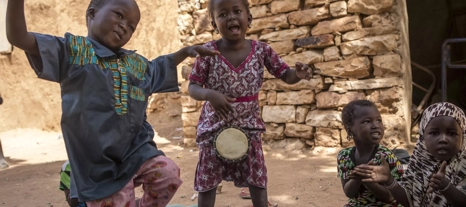 Yatè Seyba (centre) joue Tam-tam avec ses camarades de classe dans la cour du Centre de développement de la petite enfance (ECDE) dans le village de Kendie. Grâce à la Fondation H & M et à l'UNICEF Suède, les enfants de ce village reculé du Mali ont accès à l'éducation préscolaire. Au Mali, seulement 3% des enfants ont accès aux services préscolaires. Village de Kendie, cercle de Bandiagara, région de Mopti