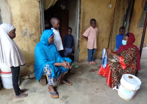 A volunteer hygiene promoter talking to a family