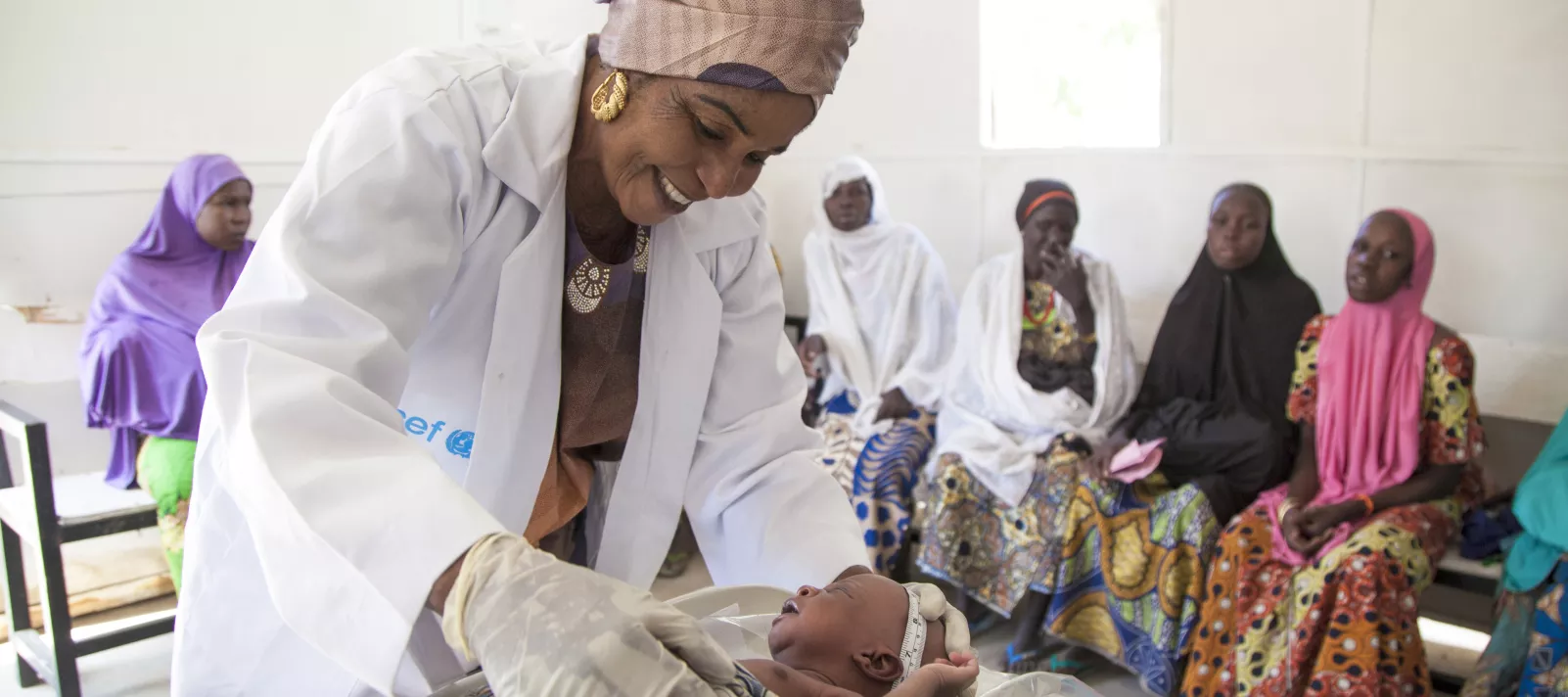 Amina Shallangwa, a UNICEF-supported midwife, measures the head of a newborn baby at a UNICEF-supported health clinic in Muna Garage IDP camp, Maiduguri, Borno State.