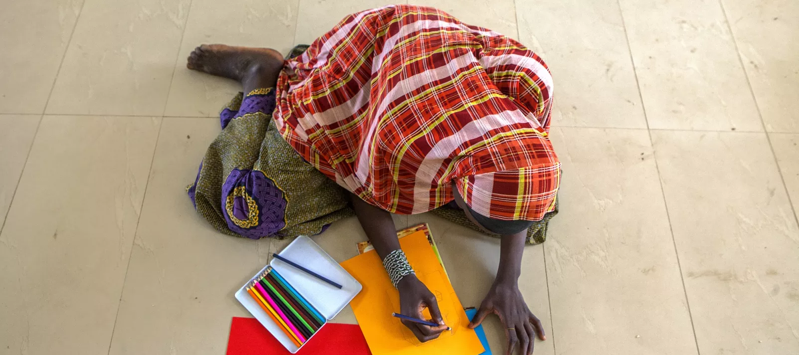 A girl drawing on coloured paper in an IDP camp in northeast Nigeria.