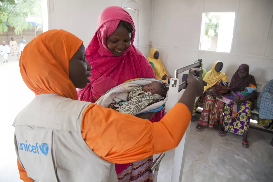 A new born baby and her mother are weighed in a UNICEF-supported health clinic in Muna Garage IDP camp, Maiduguri, Borno State.