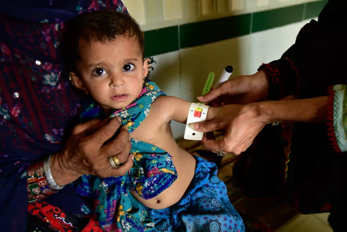 Mid upper arm circumference of an infant girl is being checked to determine her nutrition status