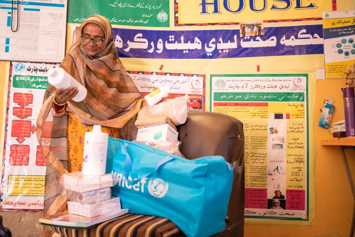 Farida examines the contents of her LHW kit while standing in the Health House, an allotted room in her home.  