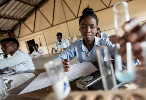 O adolescentă realizează un experiment la ora de chimie în Zambia.
