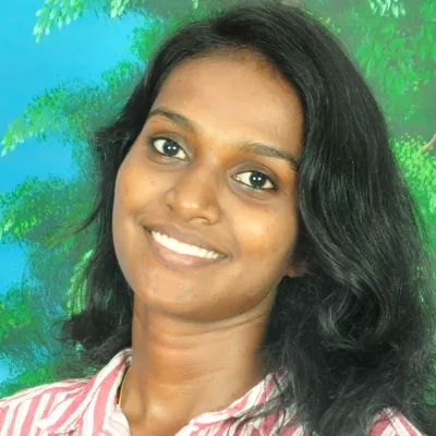 Ahallya smiles at the camera against a blue-green background