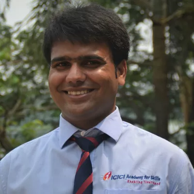 Krishnakumar smiles at the camera in a blue ICICI Academy for Skills button-up and tie.