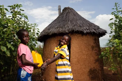 Des enfants s’aident mutuellement à se laver les mains à l’aide d’eau et de cendre dans le village de Gbandu.