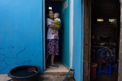 A mother holding a child at a toilet doorway