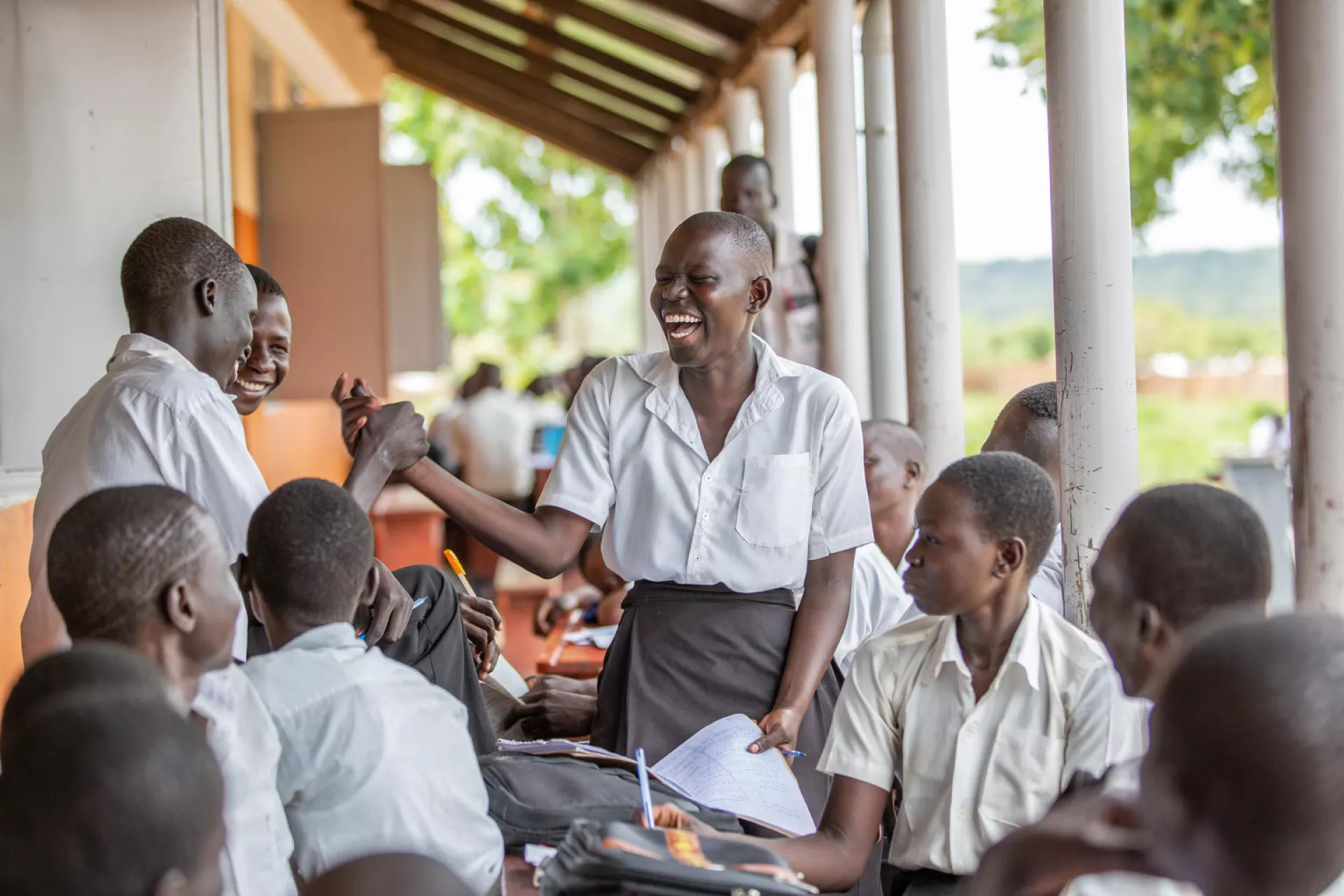 A 17-year-old girl laughs with friends outside their school in Uganda, 2019.