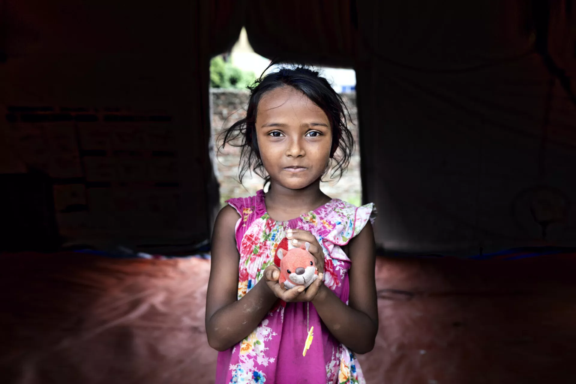 Meem (5) holds her toy while standing inside a child protection hub supported by UNICEF.