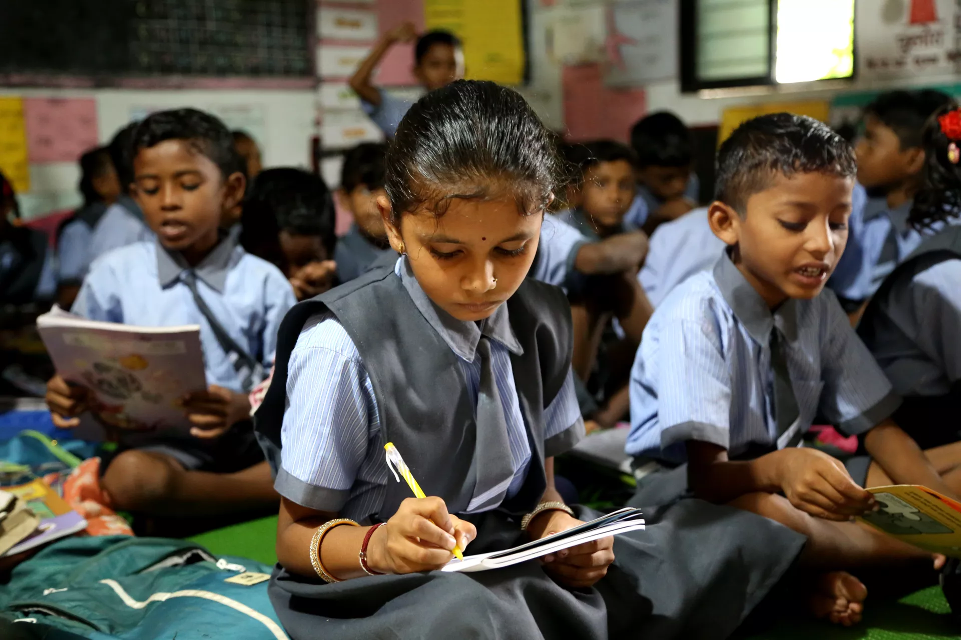 Avantika, de nueve años, fotografiada mientras escribe en su salón de clases en India.