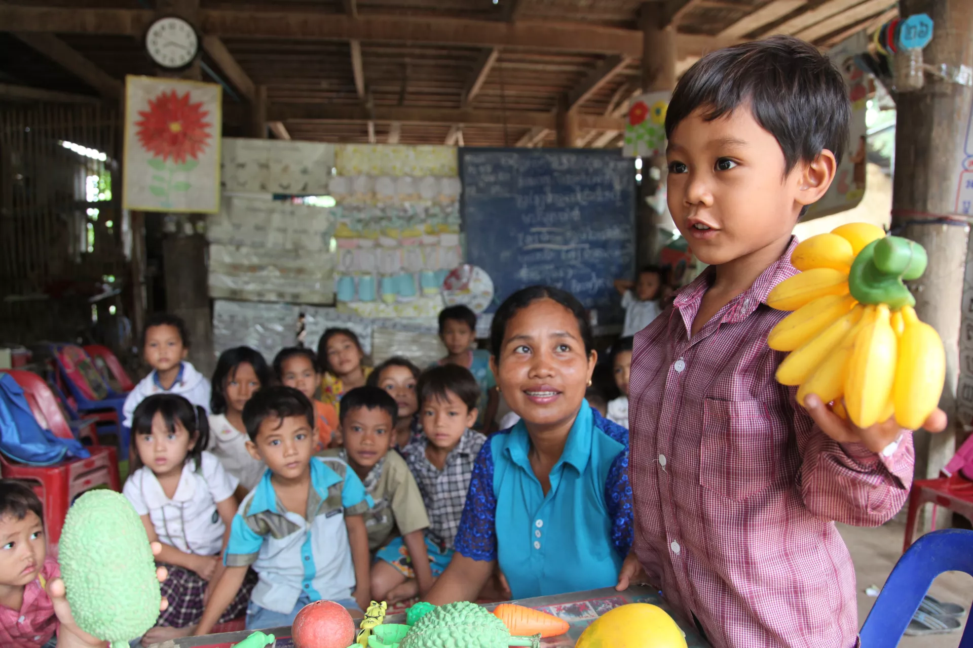 A child holds up plastic bananas during a class at a community pre-school in Sokang Commune, Cambodia, in 2015. 