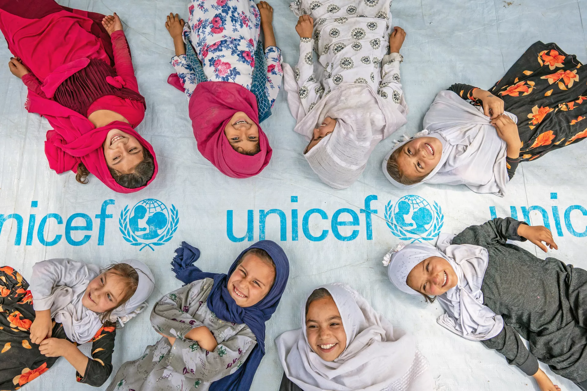 Des petites filles posent devant le logo de l'UNICEF