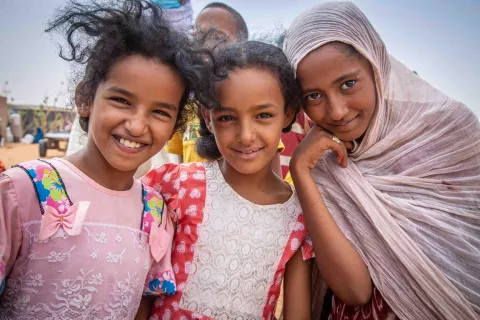 Three Malian girls pose outside the food distribution center in Mbera camp.