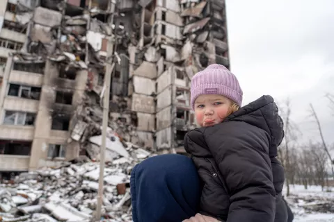 Una niña en los hombros de su papá entre los escombros en Saltivka, Ucrania