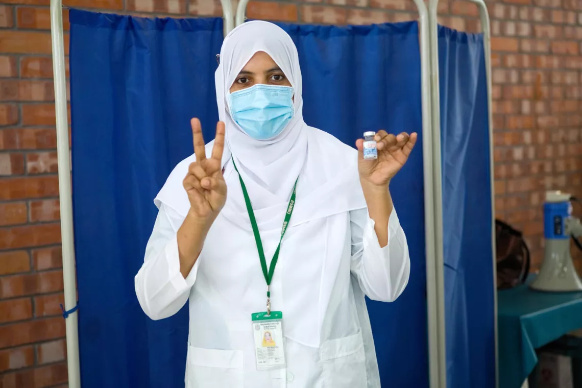 Trained vaccinator Moriom Nesa shows the victory sign after vaccinating people with COVAX donated vaccines at a hospital in Dhaka, Bangladesh.