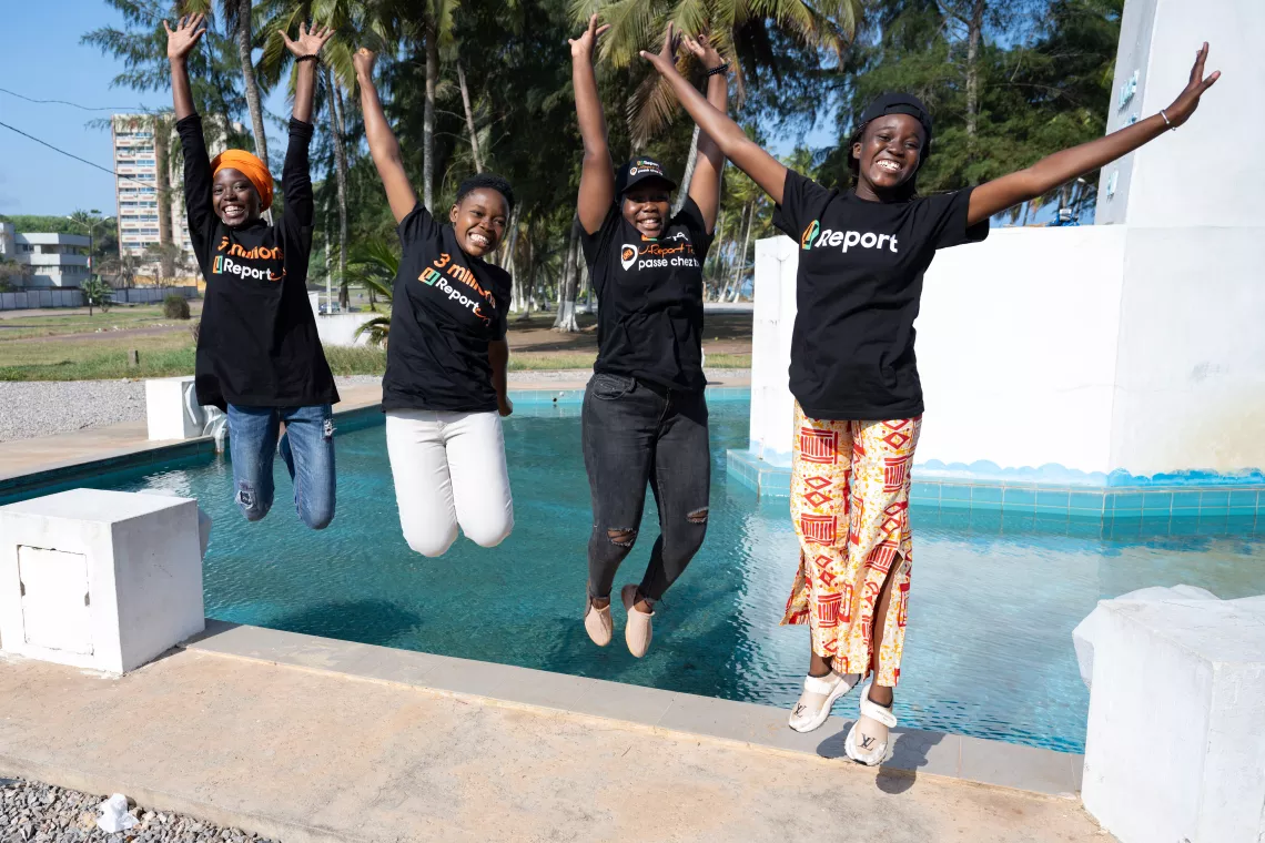 A group of young people wearing U-Report t-shirts jumping for joy