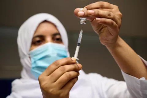 A vaccinator wearing a mask is diluting the COVID-19 concentration vaccine with sodium chloride to start vaccination in Dhaka, Bangladesh.
