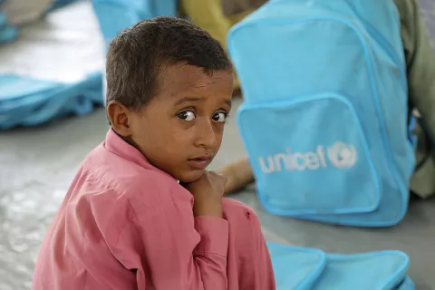 A boy sits by a backpack in a UNICEF-supported temporary learning centre in Pakistan.
