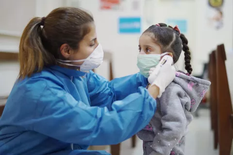A doctor takes a girl's temperature in Lebanon.