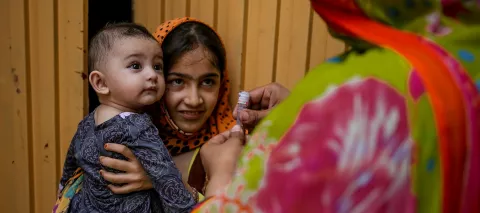 In 2017 in Khyber Pakhtunkhwa, Pakistan, a frontline health worker prepares to immunize a baby against polio in Shahin Muslim Town in Peshawar District.