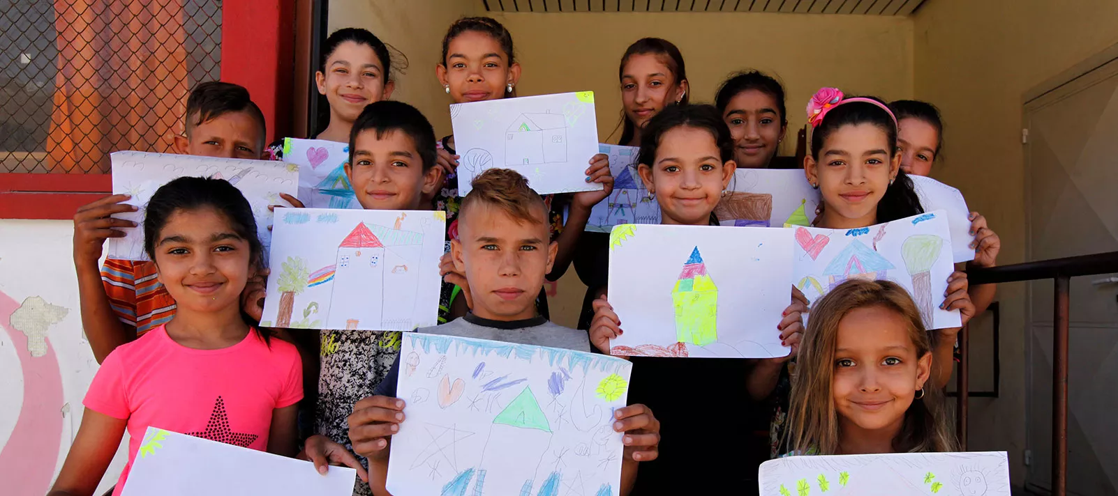 A group of children pose showing their drawings during educational activities held at UNICEF supported Child and Youth Zone, in Bulgaria, in November 2016. 