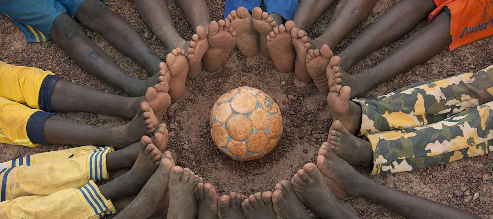 Circle of boys' bare feet with the soccer ball at a UNICEF Child-Friendly Space in Ouahigouya, Burkina Faso.