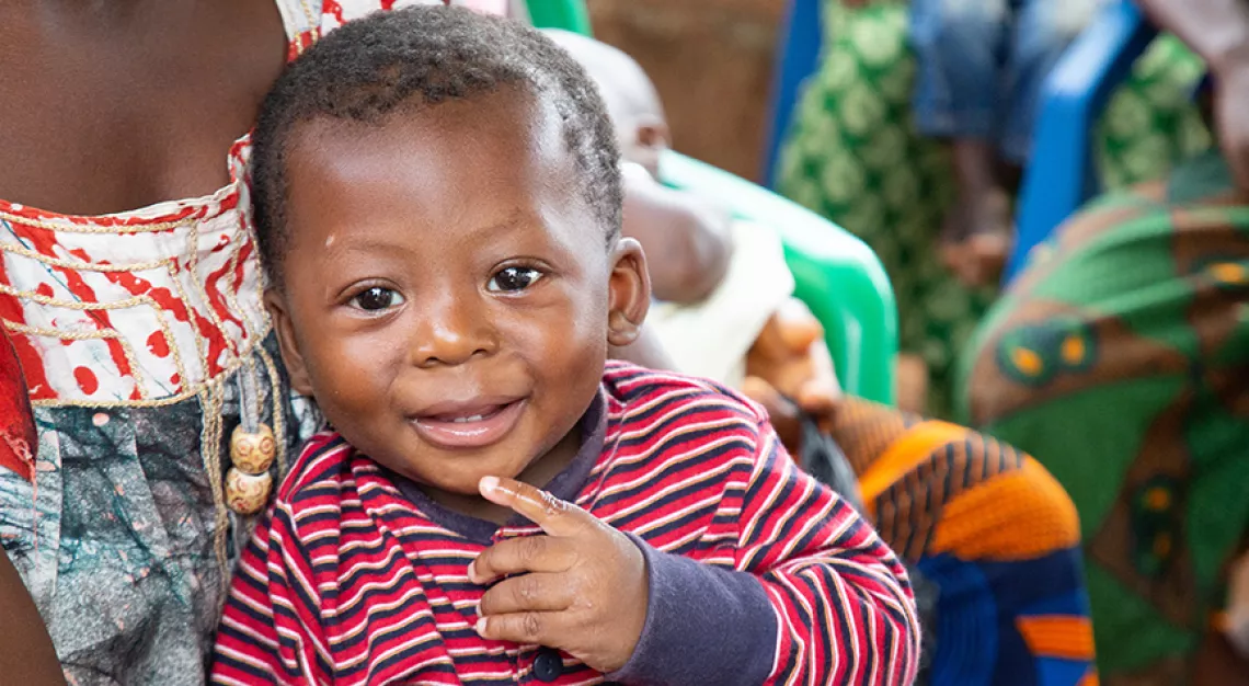 A smiling young boy in a woman's lap in in Yamoussoukro Ivory Coast, in April 2019.