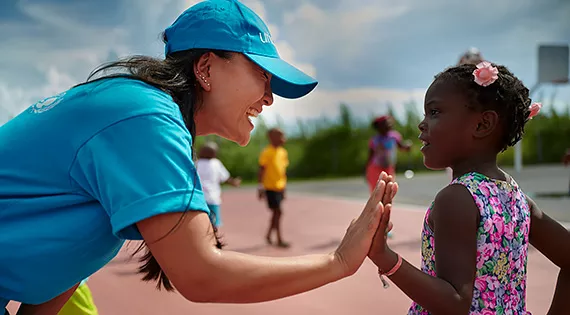 A woman wearing UNICEF t-shirt and cap greets a girl who was evacuated in the aftermath of Hurricane Dorian, in Bahamas, in September 2019. 
