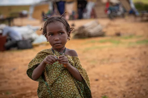A little girl standing outside in a dry area