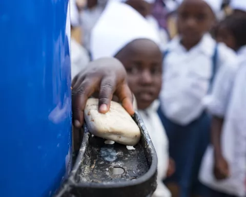 A young student washes her hands