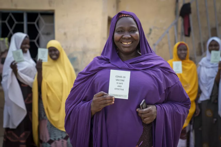 A group of women smile as they show their COVID-19 vaccination cards