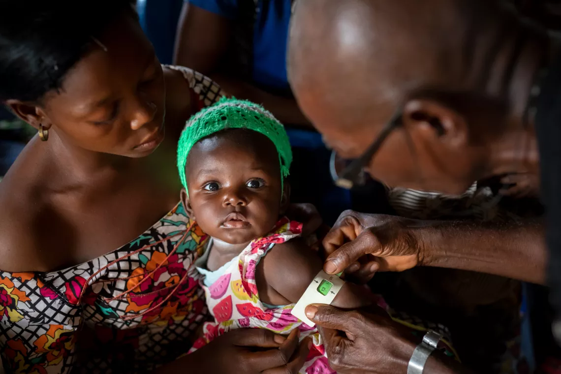 A mother holds her baby as she gets screened for malnutrition